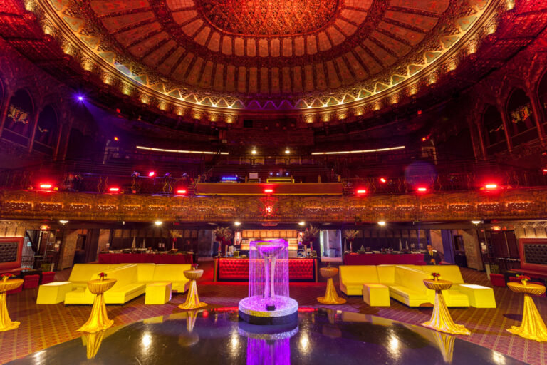 Yellow lounge seating surrounds a glowing purple centerpiece beneath the ornate dome of an indoor event hall.