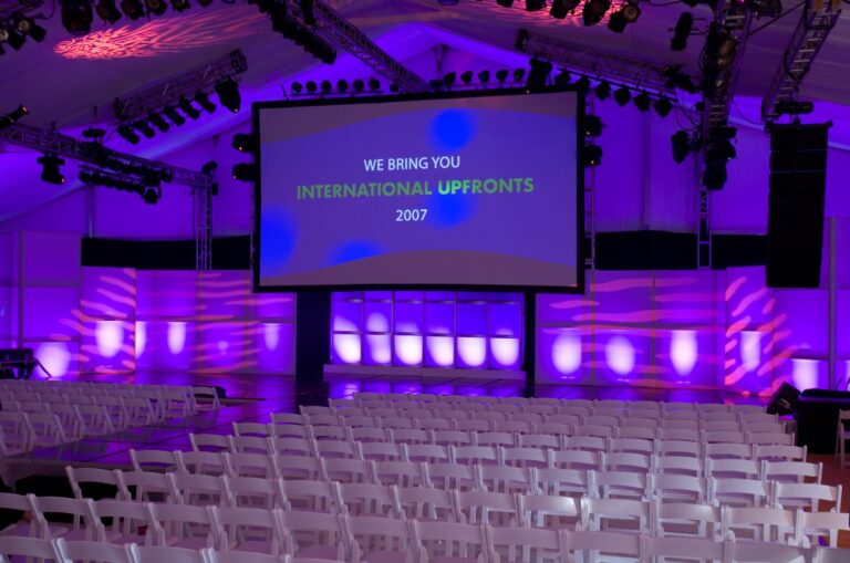 Wide view of the International Upfronts 2007 stage with branded red backdrop and dual screens, photographed in Los Angeles.