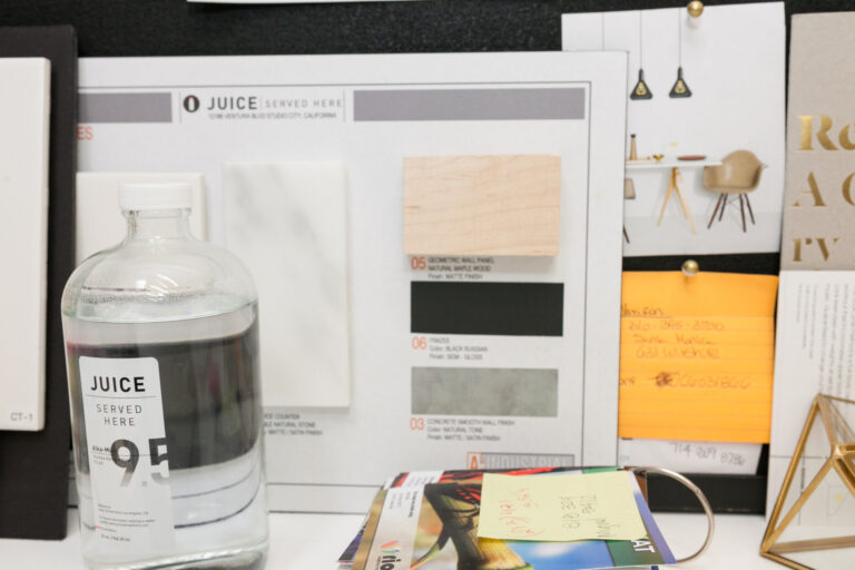 Juice bottle and printed color, packaging and product-reference sheets arranged on a tabletop.