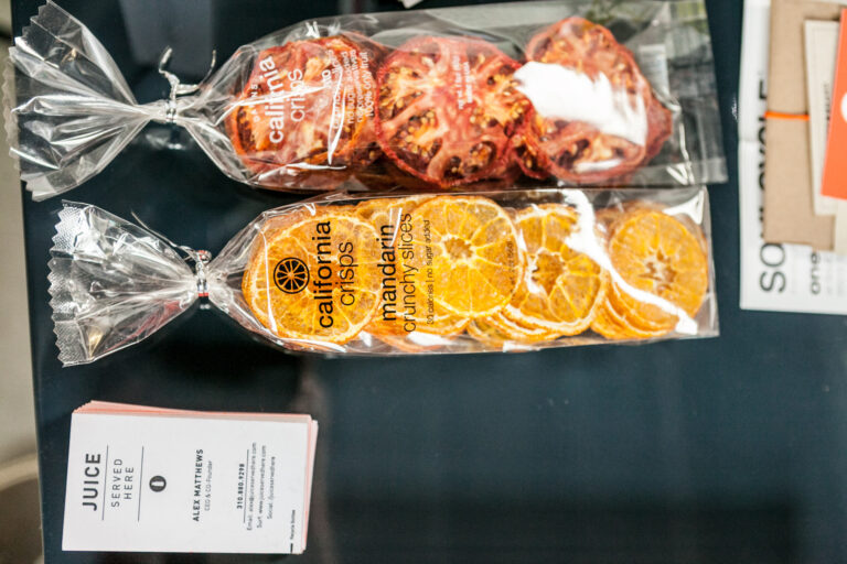 A framed Juice Served Here group cleanse product insert rests on a patterned textile.