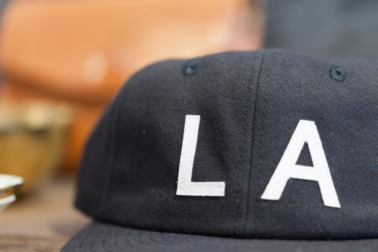 Close-up of a dark baseball cap embroidered with large white LA letters.