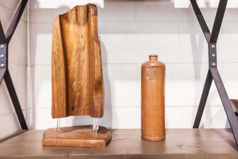 Sculptural wood vessels and a tall carved wooden piece displayed on a shelf.
