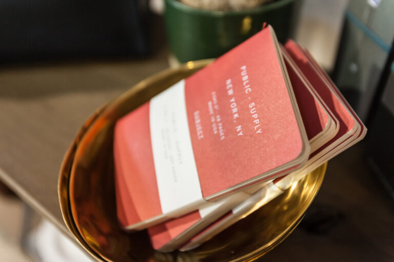 A red printed booklet or card rests inside a shallow brown leather tray.