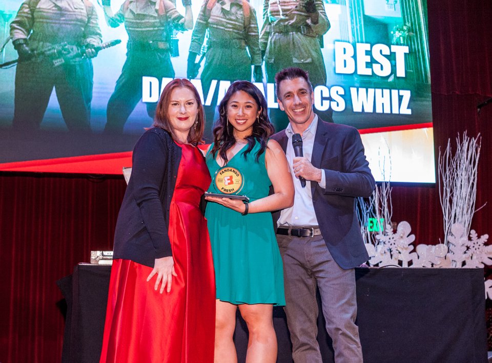 Three attendees holding an award on a corporate event stage.