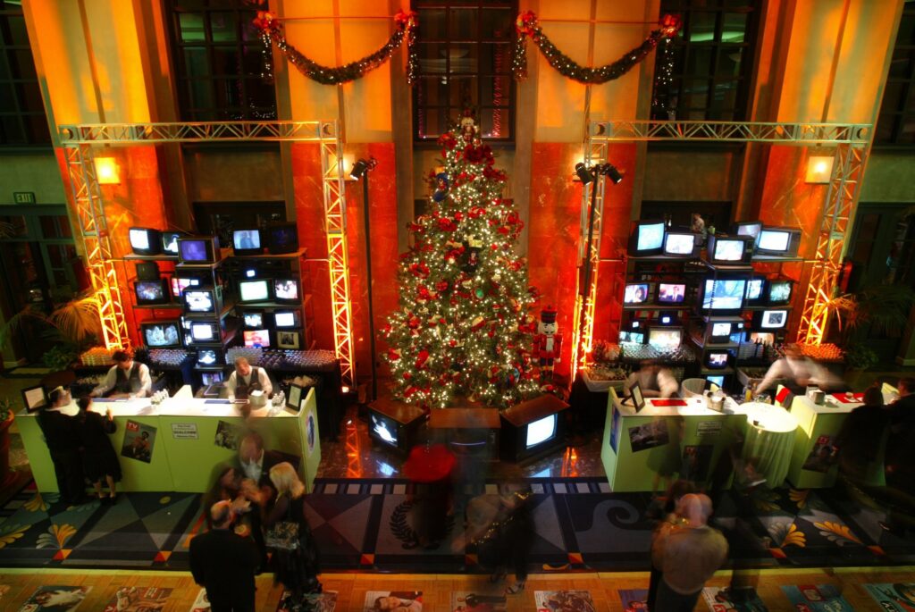 Christmas tree and video screens in a warmly lit ornate event interior.