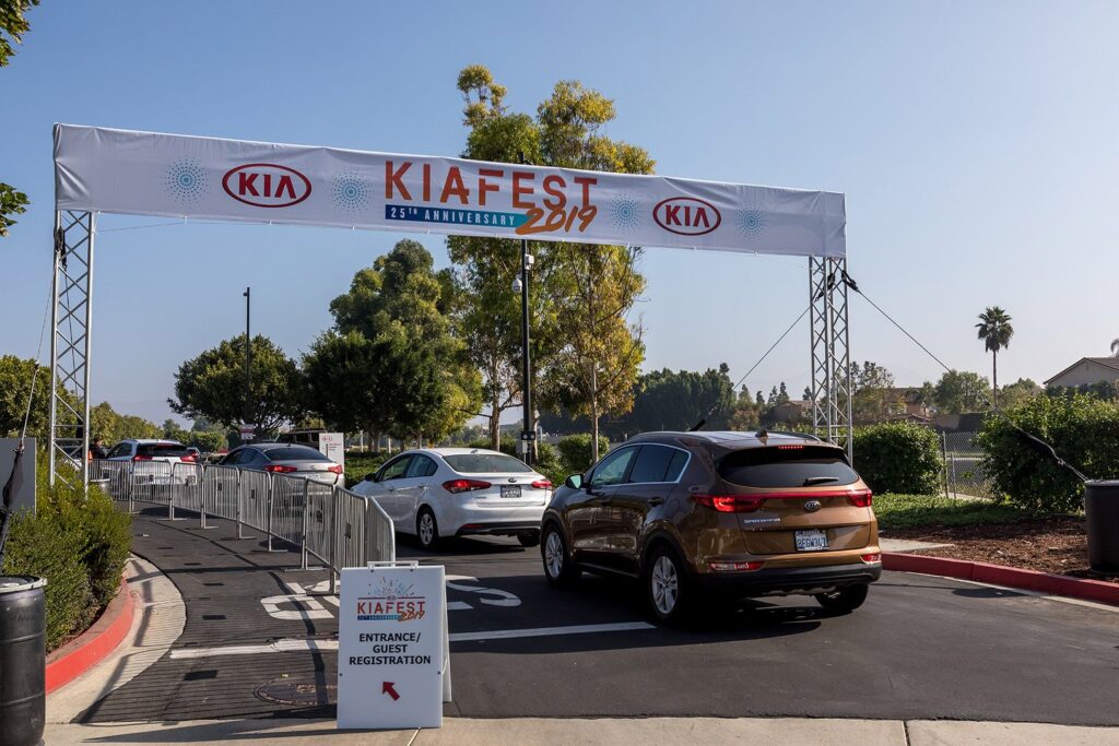 Kia Fest entrance arch above arriving vehicles with a guest registration sign.
