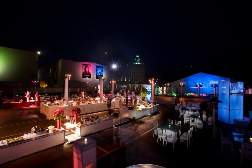 Guests mingling among illuminated food stations at an outdoor evening reception.